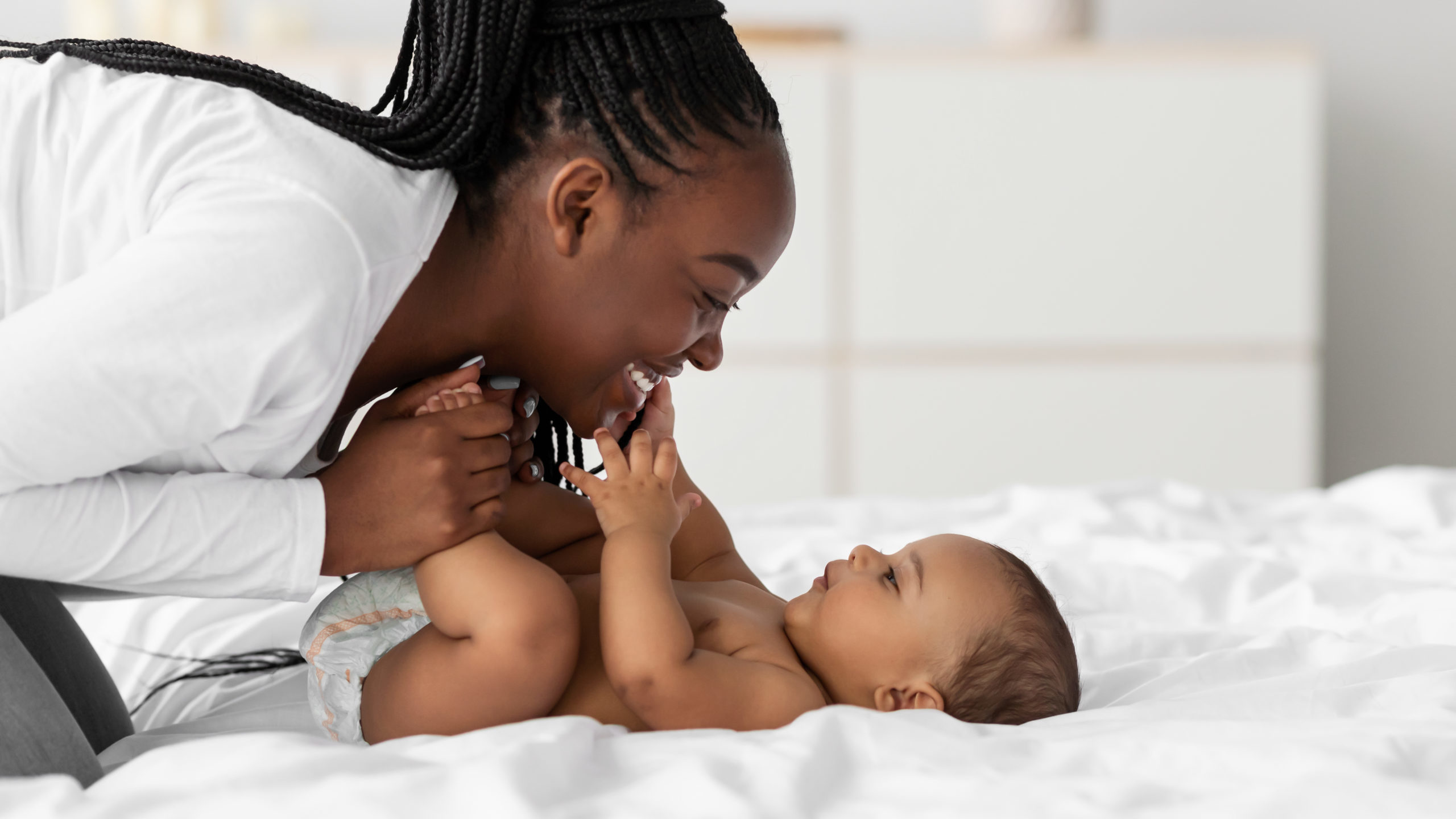 African American mom playing in bed with her black baby